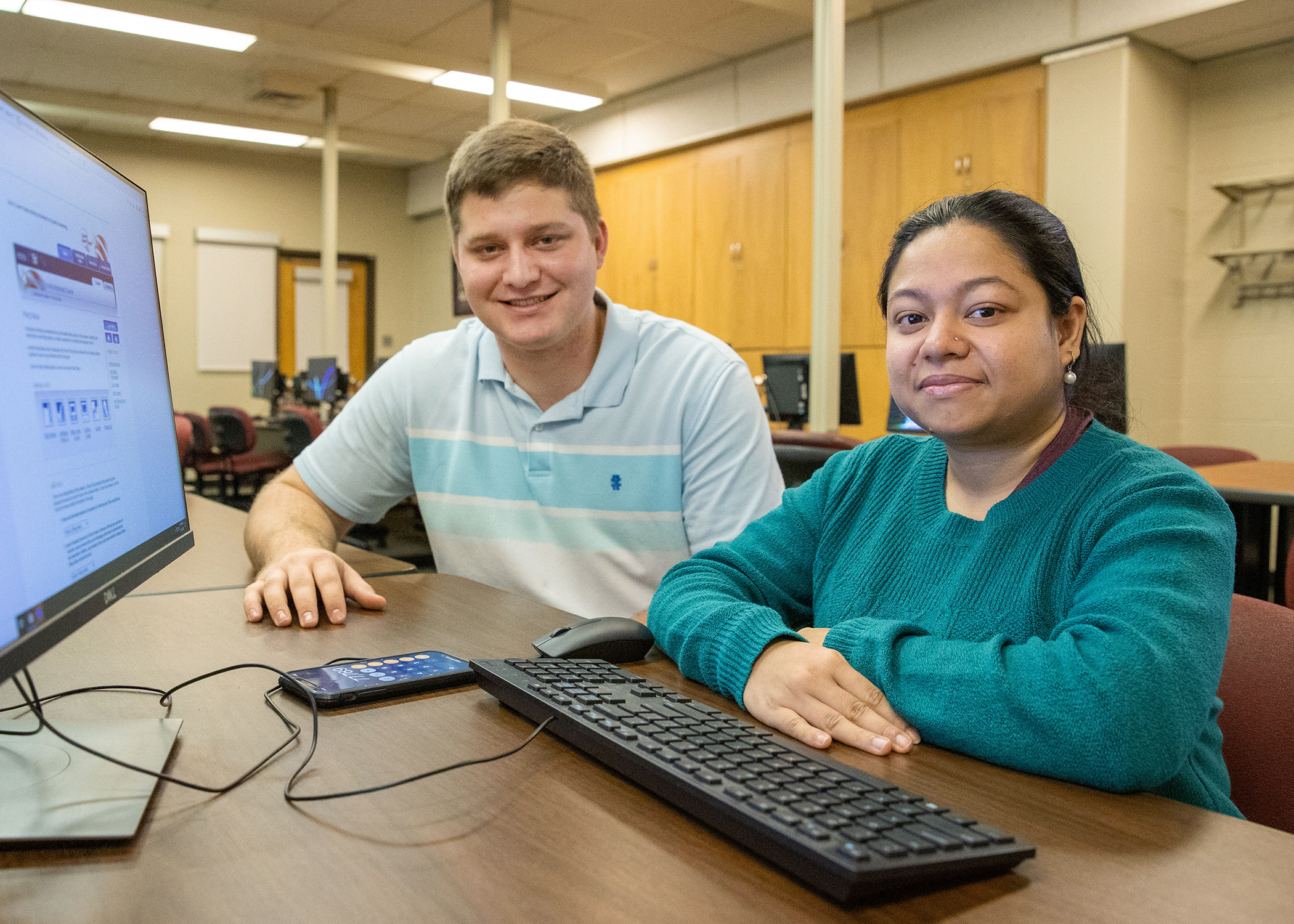 two students smiling with IRS forms on the desk in front of them